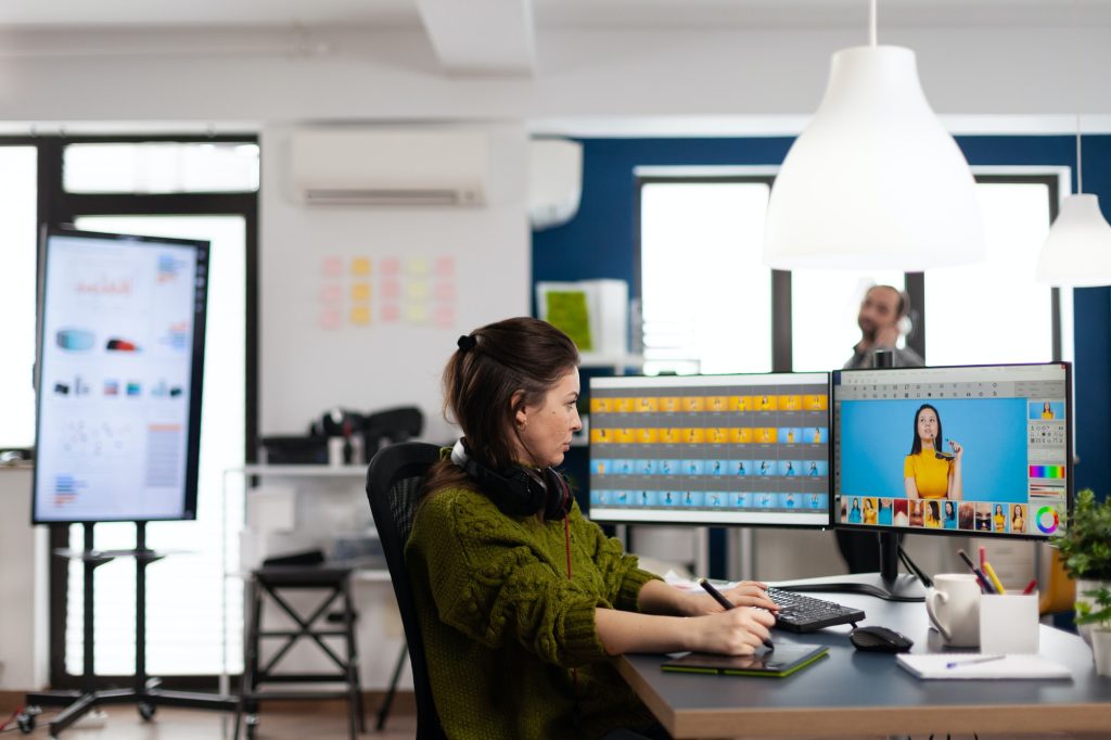 Creative photographer using digital retouching program, wearing headphones